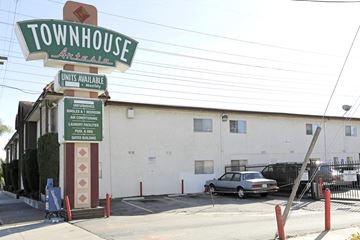 Bellflower multi-family for rent - A sign for Townhouse Antelain with a car parked in front.