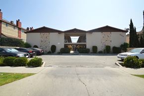 Baldwin Park multi-family for rent - A large white building with a stone facade and a brown roof.
