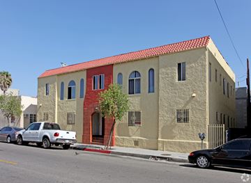 Huntington Park multi-family for rent - A white car is parked in front of a tan building with a red tile roof.