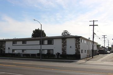 El Monte multi-family for rent - A street view of a residential area with a white building and a tree.