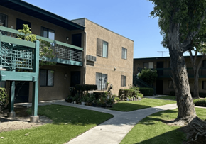 Commerce multi-family for rent - A building with a green railing and a tree in front.