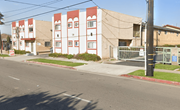 Commerce apartment for rent - A street view of a red and white building with a green fence in front.