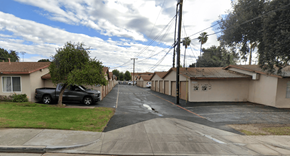 Pomona multi-family for rent - A residential street with houses on both sides and cars parked on the side.