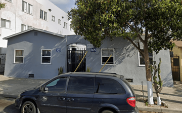 Los Angeles multi-family for rent - A grey car is parked in front of a grey building with a tree in front of it.