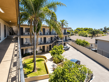 Lynwood multi-family for rent - A view of a courtyard with a palm tree and a building in the background.
