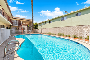 El Monte multi-family for rent - A swimming pool surrounded by a fence and a building in the background.