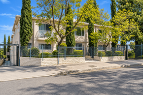 Tujunga multi-family for rent - A large house with a black fence and trees in front.