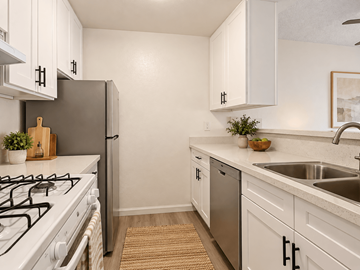 Tujunga multi-family for rent - A kitchen with white cabinets and a black fridge.