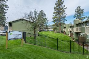 Spokane multi-family for rent - A sign for Forest Park Courtyard Apartments is in front of a black fence.
