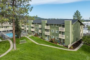 Spokane multi-family for rent - Apartment complex with a green lawn and a tree.