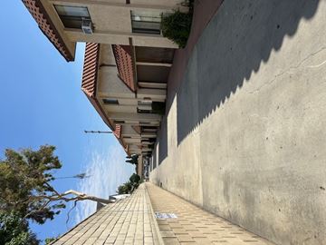 Paramount multi-family for rent - A view of a street with a building on the left and a wall on the right.