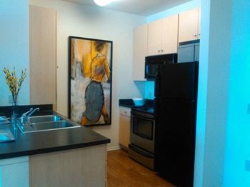 A kitchen with a black refrigerator freezer next to a black stove top oven