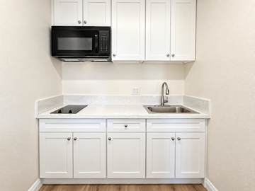 El Monte multi-family for rent - A kitchen with white cabinets and a black microwave.