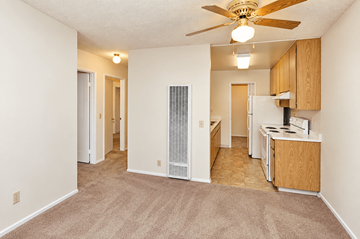 Fallbrook multi-family for rent - A living room with a fan and a kitchen area in the background.