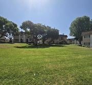 San Ysidro multi-family for rent - A sunny day in a grassy field with trees and houses in the background.