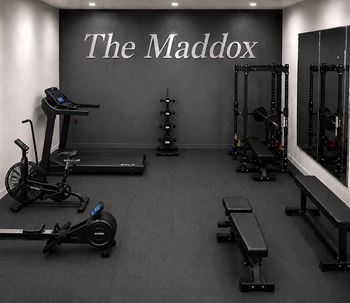 A gym with a variety of equipment including treadmills, rowing machines, and weight racks.
