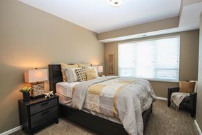 Eagan apartment for rent - a bedroom with a bed and nightstand with a lamp on top of it at The Flats at Cedar Grove, Eagan, MN, 55122
