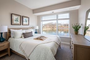 Prior Lake apartment for rent - A bedroom with a large bed and a view of a lake through the window.