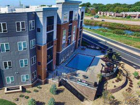 Eagan apartment for rent - an aerial view of a building with a pool in front of it at The Flats at Cedar Grove, Eagan