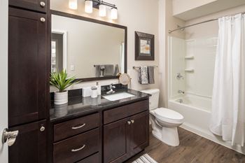 A bathroom with dark cabinets and a white bathtub