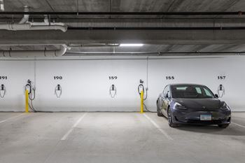 A tesla car parked in a parking garage next to a charging station