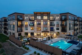 Prior Lake apartment for rent - A modern apartment complex with a pool at dusk.