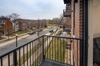 A balcony with a black railing and a street in the background