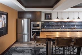 Burnsville apartment for rent - a community room with a kitchen with dark cabinets and a wooden table at The Gallery Apartments, Minnesota, 55337