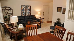 Parkville apartment for rent - A living room with a black leather couch, a wooden coffee table, and a lamp at Kensington Gate Apartments, Parkville