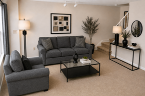 Essex townhouse for rent - A living room with a grey couch, a grey armchair, a black coffee table, and a small tree.