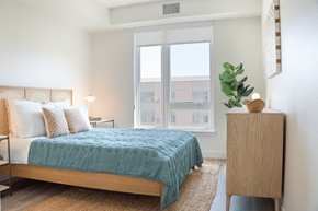 Davis apartment for rent - A bedroom with a bed, nightstand, and a plant.