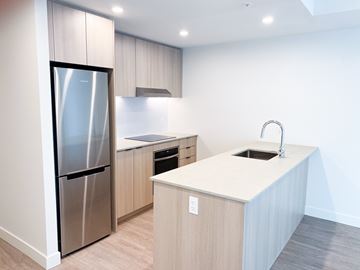 Surrey apartment for rent - A modern kitchen with a stainless steel refrigerator and a white countertop.