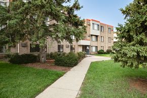St Paul apartment for rent - A building with a red stripe on the side is surrounded by greenery.