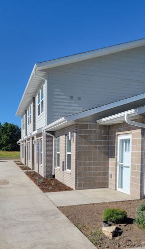 Ottumwa townhouse for rent - A building with a grey roof and white walls with a clear blue sky in the background.