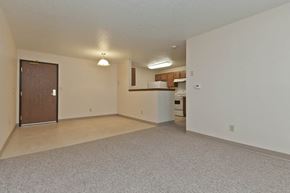 Des Moines apartment for rent - A spacious room with a door and a kitchenette in the background.