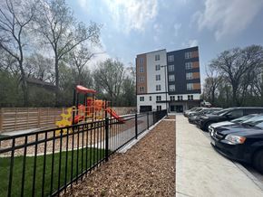 St. Paul apartment for rent - a playground in front of a building with cars parked in a parking lot