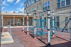 Minneapolis apartment for rent - A playground with a blue climbing structure on a brick patio.