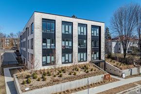 Minneapolis apartment for rent - A modern building with a grey and black facade and a small garden in front.