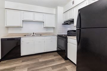 Kansas City apartment for rent - A black refrigerator is on the right in a kitchen with white cabinets.