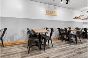 Bentonville apartment for rent - A dining area with chairs and tables in front of a wall with the word MELD on it.