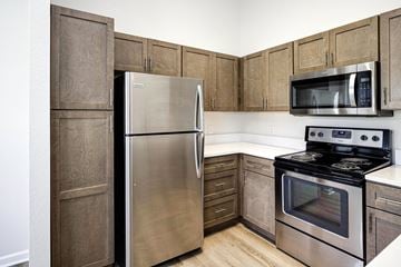 Omaha apartment for rent - A kitchen with a stainless steel refrigerator, microwave, and oven.