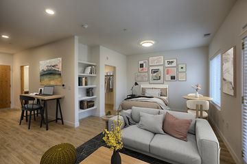 Omaha apartment for rent - A living room with a grey couch and a desk with a laptop.