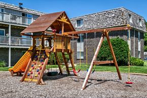 Bellevue apartment for rent - a wooden swing set in a playground in front of a building