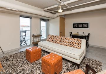 Des Moines apartment for rent - A living room with a white couch and orange ottoman.