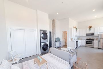 Omaha apartment for rent - A modern living room with a grey sofa and a kitchen in the background.