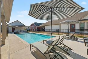 Rogers apartment for rent - A striped umbrella is over a lounge chair by a pool.