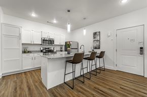Pea Ridge apartment for rent - A kitchen with white cabinets and a wooden floor.