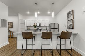 Pea Ridge apartment for rent - A kitchen with white cabinets and a white island with brown barstools.