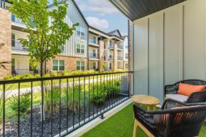 Pea Ridge apartment for rent - A balcony with a chair and a table overlooking a grassy area.