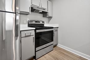 Bentonville apartment for rent - A modern kitchen with a stainless steel refrigerator and an oven with a stove on top.